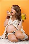 Happy pregnant woman on the floor eating pickles