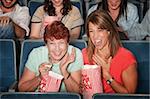 Two laughing women with popcorn bags at a picture show
