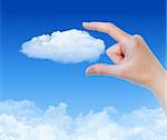 Woman hand measures the cloud against blue sky with clouds. Concept image on cloud computing and eco theme.