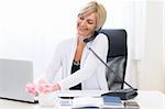 Senior business woman speaking phone and working on laptop