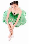 Sitting ballerina in green dress isolated on white background