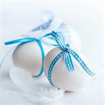 white easter eggs with blue ribbons and white feathers