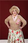 Smiling drag queen with hands on hip over maroon background