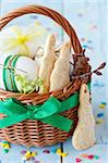 Easter bunny cookies, eggs with ribbon in a basket on an blue  wooden board.