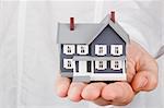 Close-up photograph of a miniature house in a man's hand.