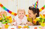 Porträt der glückliche Mama und Baby Essen Geburtstagskuchen