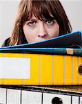 Exhausted business woman in the office with a pile of folders at front