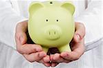 Close-up photograph of a green piggy bank in man's hands.