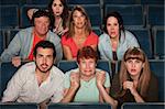 Group of scared people watching movie in a theater