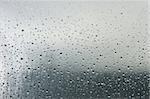 Water droplets on a transparent surface. On the background the blurry objects