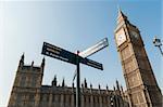 Low angle shot of Big Ben in London, with directions sign in the foreground pointing to famous tourist attractions around the area.