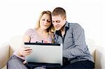 Happy young couple with a laptop sitting on the couch