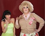 Curious drag queen and friend with cigarettes over maroon background