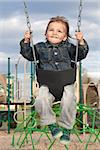 A young boy swinging at the playground on a beautiful spring day.