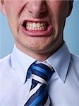 closeup of businessman screaming against blue background. Vertical shape
