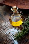 Extra virgin healthy Olive oil with fresh rosemary on rustic wooden background