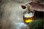 Extra virgin healthy Olive oil with fresh rosemary on rustic wooden background