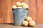 Old bucket filled with potatoes against a rustic background