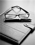 Reminder book with a pen and a pair of glasses