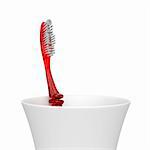 Red plastic toothbrush in a plastic cup