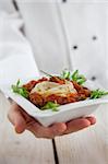 Male chef in restaurant kitchen is garnishing and preparing pasta dish