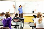 Students raise their hands to solve a problem in algebra class.