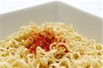 Instant noodles with chili powder on top in a white square bowl