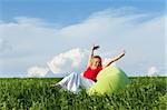 Happy woman in inflatable armchair outdoors on the green spring field