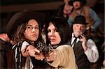 Two pretty cowgirls point revolvers at the camera