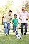 Grandfather With Son And Grandson Playing Football In Park