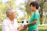 Grandfather And grandson In Park With Football