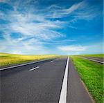 green field and road over blue sky