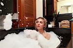 Pretty woman laying in bath with foam