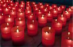 lighted candles in the red container in a church