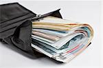many banknotes in black wallet on light background