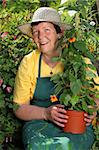 Photo of a retired woman holding a potted plant she is about to put into her garden.