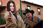 Pretty woman and partner aim guns in old west town