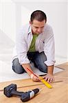 Man laying laminate flooring - measuring a plank
