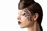 very cute young girl with letter and number painted on her face and a nice creative hair style, she is turned in profile at right and looks down
