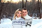 Happy pair in winter forest dressed in sweater