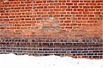 Background of ancient grunge aged red brick wall and snow in winter.