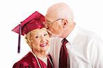 Senior woman earns a college degree and a kiss from her husband.  Isolated on white.