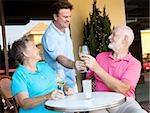 Waiter serving wine to a senior couple at a restaurant.