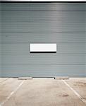 Concrete parking floor and tin wall with blank info board.