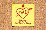 Sticky note with Happy Fathers Day on a cork bulletin board.