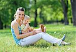 Happy mother and baby sitting on grass in park