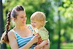 Happy mother tickling baby outside