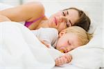 Baby and mother sleeping together in bed