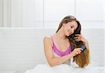 Happy woman combing beautiful long hair