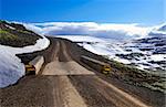 A narrow bridge allows passage of only one vehicle at time on a gravel road in the mountains of Iceland.